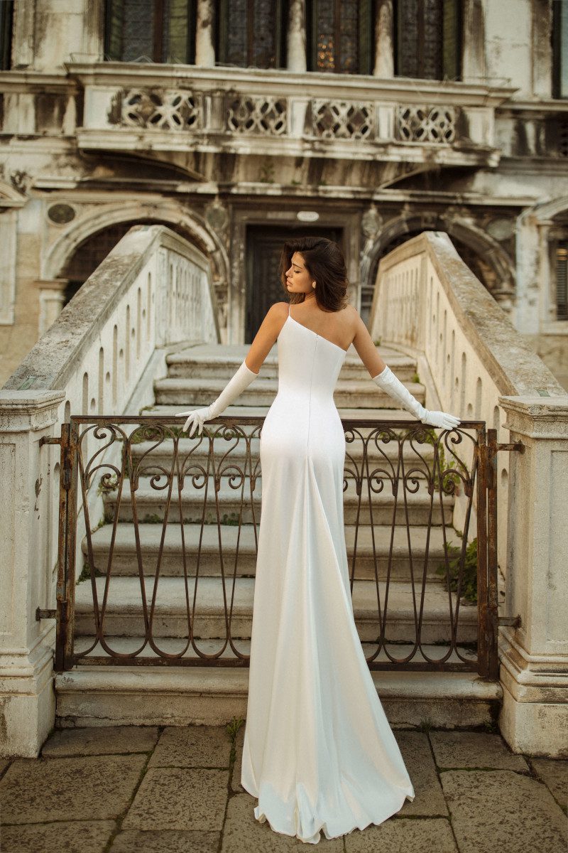 White fitted satin wedding dress Jina with a thin strap on the left shoulder by Rara Avis at Dell'Amore Bridal, Auckland, NZ. 2