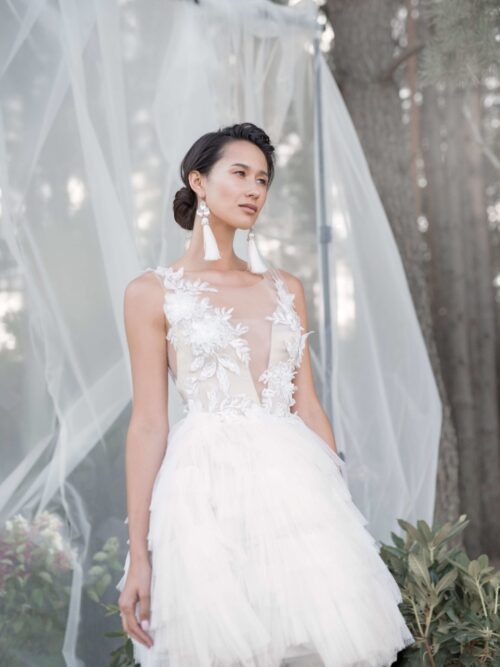 A bride wearing wedding dress with short skirt with horizontal flounces and lace bodice decorated with volume flowers by Rara Avis at Dell'Amore Bridal, Auckland, NZ. 4