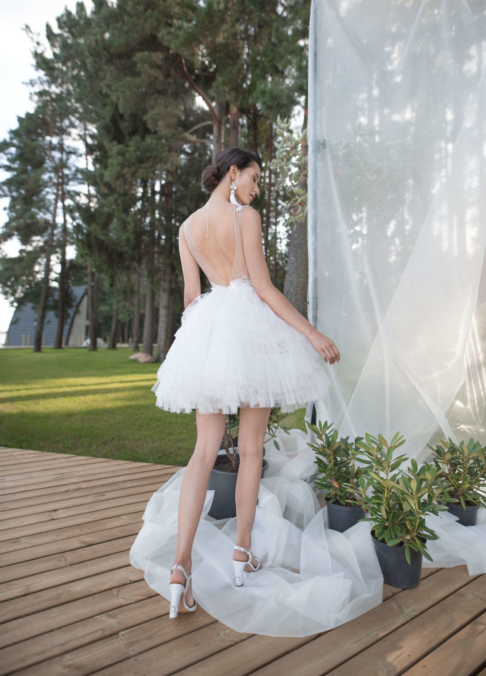 A bride wearing wedding dress with short skirt with horizontal flounces and lace bodice decorated with volume flowers by Rara Avis at Dell'Amore Bridal, Auckland, NZ. 3