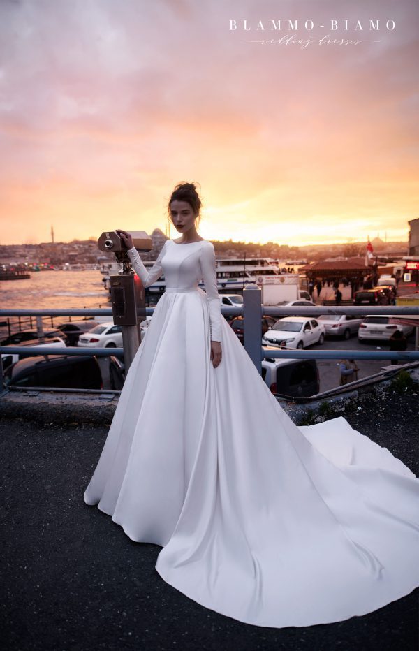 A bride wearing satin princess wedding dress Tilda by blammo-biamo with long sleeves, long train and open back with brooch by Rara Avis at Dell' Amore Bridal, Auckland, NZ. 4