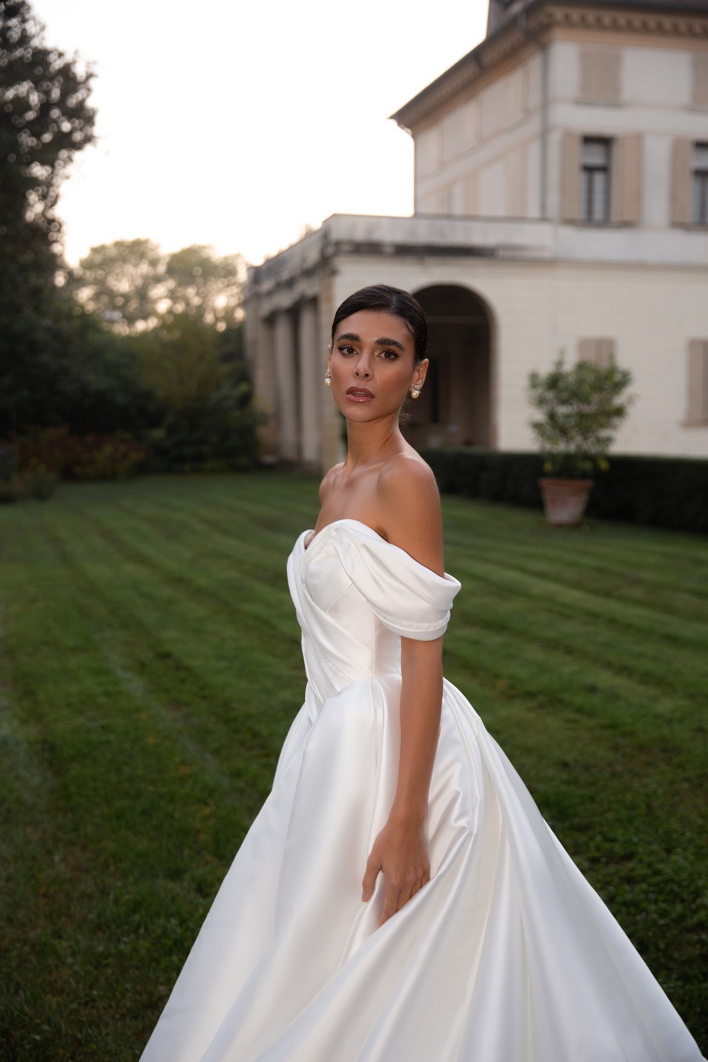 Off-shoulder satin wedding dress Shedar with wrap-over drapery corset by rara avis at Dell'Amore Bridal, NZ. 2