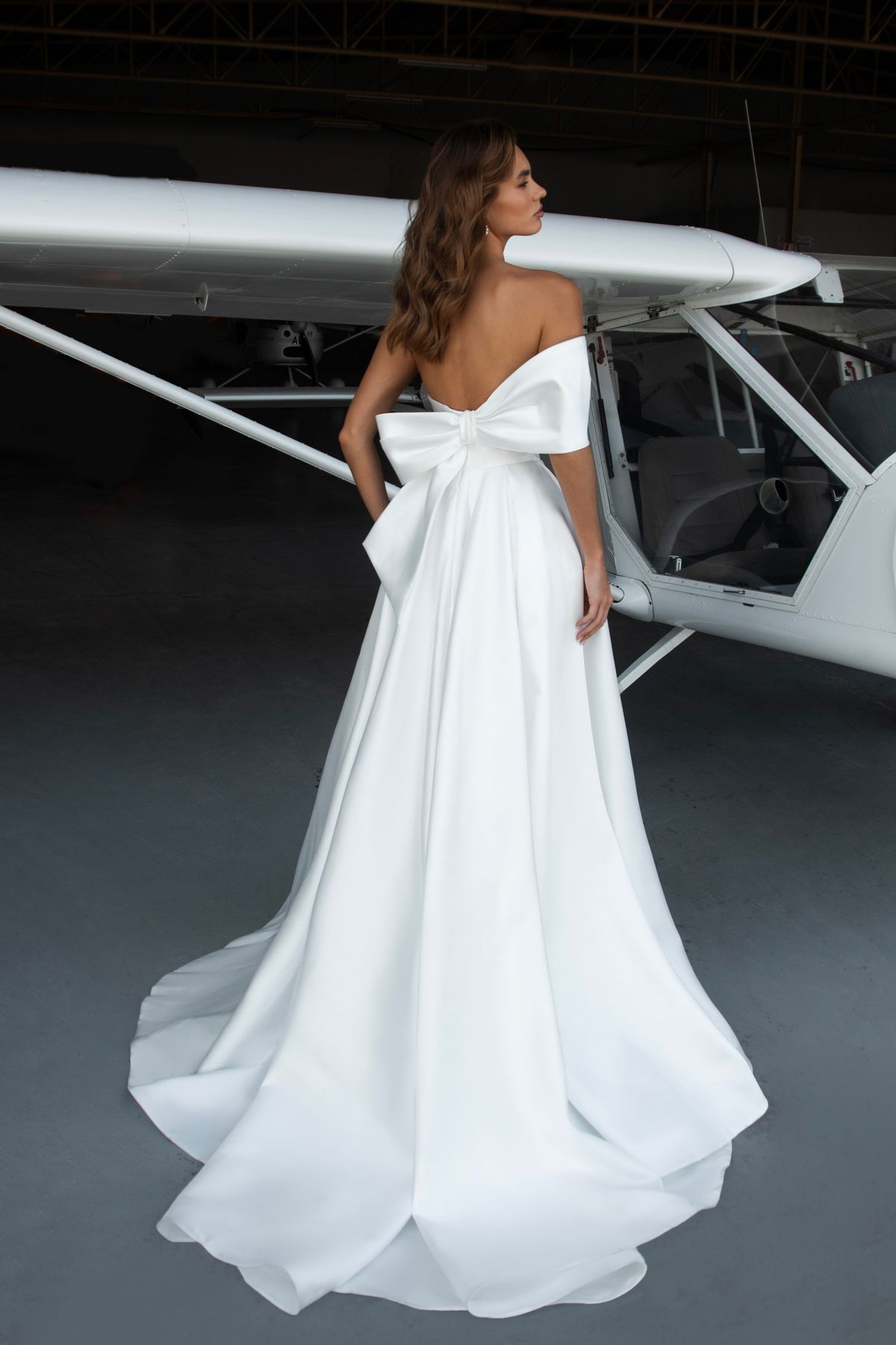 Satin wedding dress Leonie with a bow and one off-shoulder sleeves by romanova designer at Dell'Amore Bridal, NZ. 2