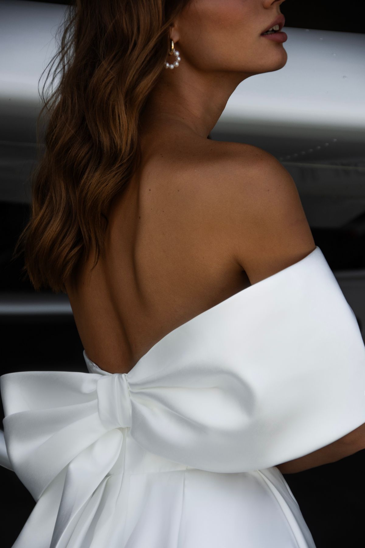 Satin wedding dress Leonie with a bow and one off-shoulder sleeves by romanova designer at Dell'Amore Bridal, NZ. 5